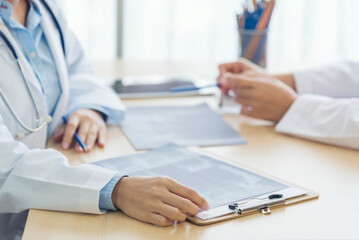 Two asian women hand doctors meeting write prescription medical clinic. Doctor discuss using laptop write note. Close up hands of two women doctor medical lab discussing together healthcare teamwork