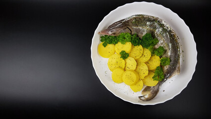 sturgeon on a white round plate baked with potatoes on a black background. cooking expensive beluga.