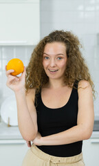 vegetarian woman smile, happy, show orange in hand, looking at camera in kitchen. beautiful caucasian woman cooking healthy diet fruit or vegetable in kitchen