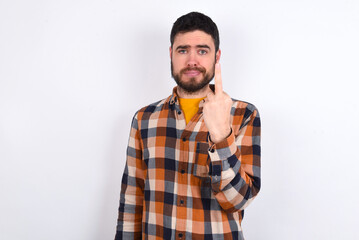 young caucasian man wearing plaid shirt over white background shows middle finger bad sign asks not to bother. Provocation and rude attitude.