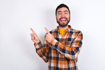 Fototapeta premium young caucasian man wearing plaid shirt over white background points at copy space indicates for advertising gives right direction