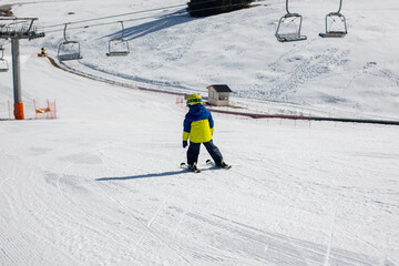 Cute toddler child in colorful ski wear, skiing in Italy on a sunny day, kids and adults skiing together
