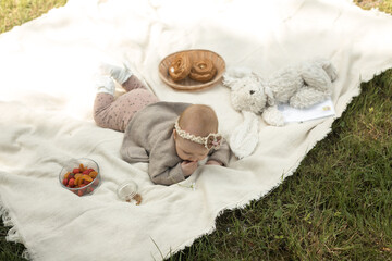 Fototapeta na wymiar little girl lies on a blanket at a summer picnic