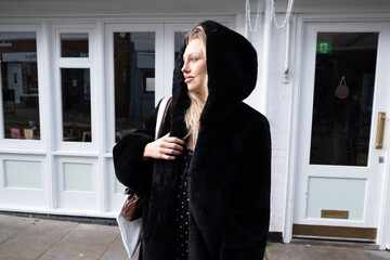 Beautiful Woman with a winter black coat holding the hood