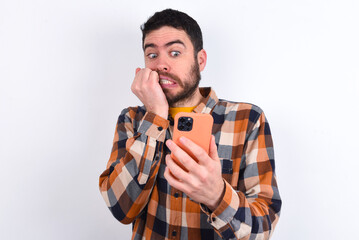 Portrait of pretty frightened young caucasian man wearing plaid shirt over white background...