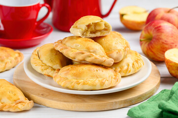 Obraz na płótnie Canvas Baked pasties stuffed with apples. Pirozhki - russian baked puff pastry with apple fillings. Homemade fruit pies. Selective focus