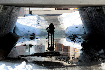 A woman walking her bicycle through wet underway