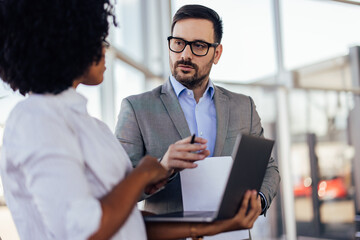 Serious bearded executive with glasses, listening to his african-american coworker.