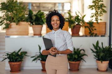 Portrait of smiling african-american woman, holding laptop, plan