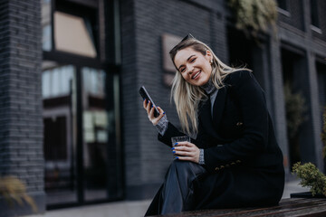 Portrait of attractive blonde woman, browsing something online, having a drink.