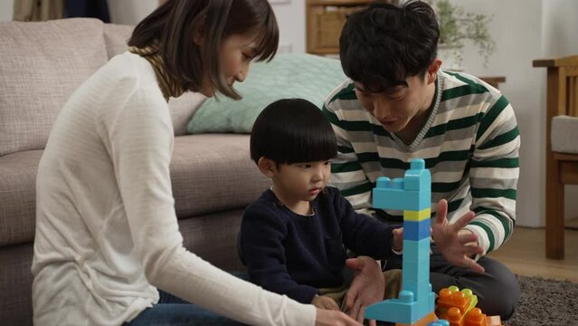 "slow motion of asian father, mother and little boy having fun with toy bricks together at home. happy dad and mom applauding and praising their son for making creative work"