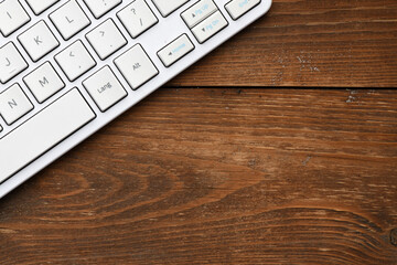 Close up white computer keyboard on wooden background. View from above.