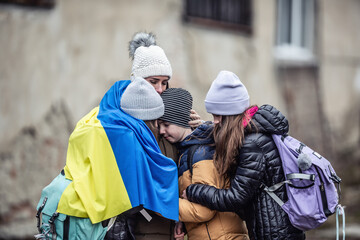 Ukrainian woman holds her three children all sad from being forced to flee their home country and become refugees - obrazy, fototapety, plakaty