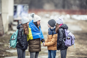 Ukrainian woman fleeing the conflict with children reassures her three kids that everything will be...