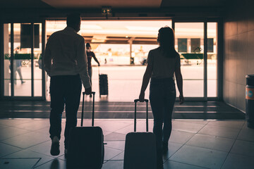 Man and woman with luggage wearing protective masks  leaving the airport