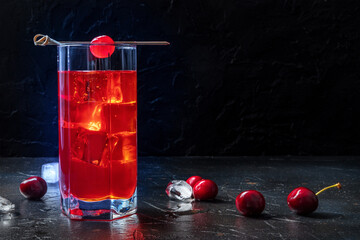 Cocktail with a cherry. Alcohol drink on a black background, with ice. Luxury beverage in a...