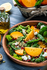 Vegetarian menu, healthy food. Healthy salad with persimmon, spinach, nuts, goat cheese, pomegranate, pumpkin seeds. Prevention of vitamin deficiency