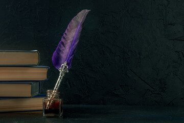Quill pen with a retro ink well and a stack of old books, a side view on a black background, the...