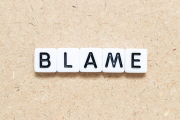 White tile alphabet letter with word blame on wood background