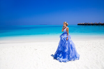 Fototapeta na wymiar Summer fashion. Elegant fashion model. Glamour, stylish female model in elegant long gown dress on the Maldives beach. Travel model. Elegance. Bride on Maldives - concept. Bridal fashion.Classy woman.