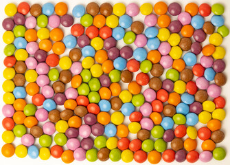 Square frame with candies, children's holiday. Chocolate dragees of different colors. Top view,