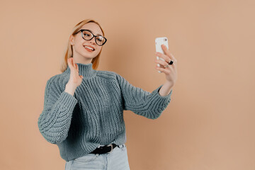 Portrait of happy young girl with straight blonde hair taking a selfie isolated against the light...