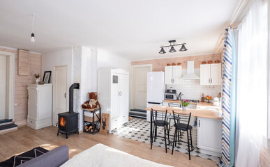 Interior of a bright studio room with a Scandinavian style fireplace in a private house, where the living room is combined with kitchen. in a country house