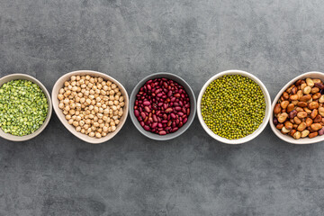 Different types of legumes in bowls, green peas and chickpeas , colored beans and maash, top view, copy space