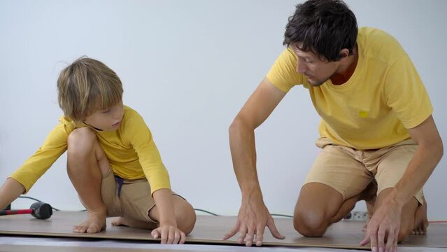 Father and his little son install laminate on the floor in their apartment. DIY concept