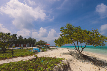Fototapeta na wymiar Empty White Sandy Beach with the Palm Trees and Blue Ocean Water on the Paradise Maafushi Island, Maldives
