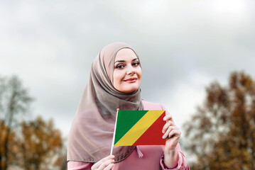 Muslim woman in hijab holds flag of Republic of the Congo
