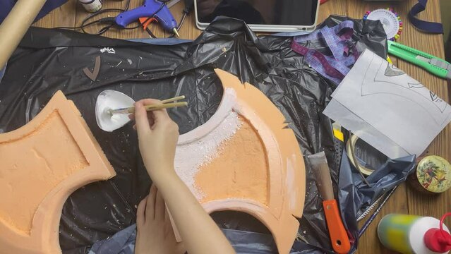 Person's hands ground piece of styrofoam with brush. Viking axe made of building materials for cosplayer festival. Diy and handicraft.
