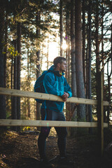 Fototapeta premium Active and exploring man in sportswear rests leaning against a railing after a hard hike, enjoying the view of the valley during sunset. Sotkamo, Finland
