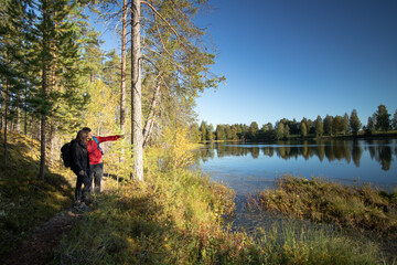 young couple stands on the edge of a lake and the man shows his girlfriend a beautiful spot on the...