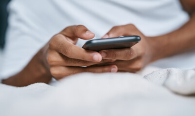 One tap is all it takes to connect. Cropped shot of a man relaxing on his bed and using a smartphone.