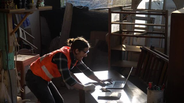 Happy and excited carpenter man celebrate to success with computer laptop with order and good news online . Business Owner wood worker In Workshop