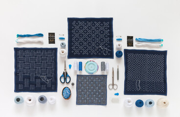 Geometric embroidery in Sashiko style with white threads on blue cotton fabric with intricate...