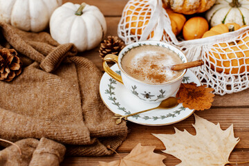 Autumn art composition - hot drink, varied dried leaves, pumpkins on wooden background, cozy autumn