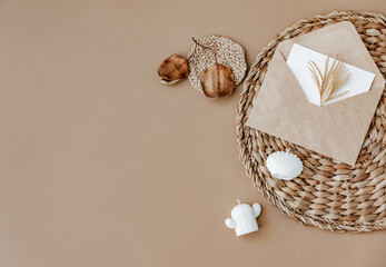 Straw stand, envelope and card, dry flowers on neutral beige background. Aesthetic minimal background. Flat lay, top view.