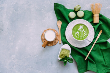 Fototapeta na wymiar Green tea latte in white cup next to matcha powder. Japanese tea ceremony concept. Detox tea. Antioxidant drink
