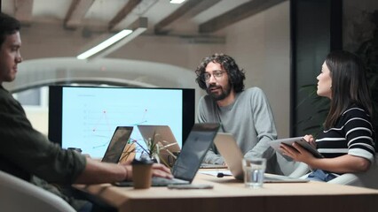 Video of smart businessman explaining a project to his colleagues with statistics on the computer on coworking place.