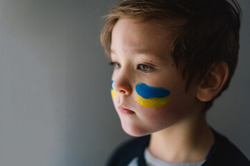 Portrait of a Ukrainian boy with a face painted with the colors of the Ukrainian flag. Ukrainian...