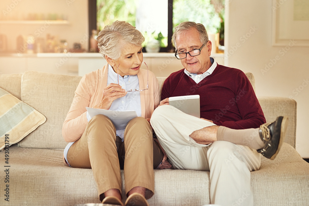 Poster using their tablet to do the grunt work. shot of an elderly couple working out a budget while sittin