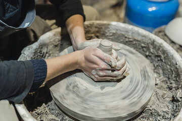 potter's female hands, soiled in clay, form clay lump on potter's wheel. Craft clay pottery, hobby folk art