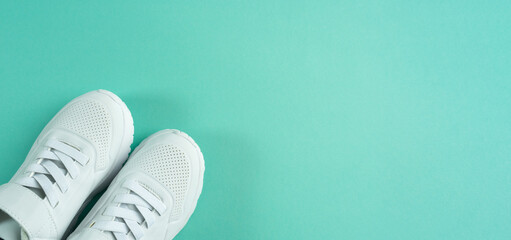 Childrens sneakers on mint background. White shoes. Copy space. Banner.