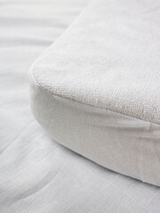 corner of the mattress with a mattress pad that does not let moisture through. White terry cotton fabric for mockup overlay design. Home textiles for the bedroom. Waterproof sheet with elastic band