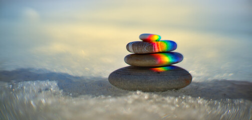 Early spring Zen rainbow stone on ice. Concept of onset of spring
