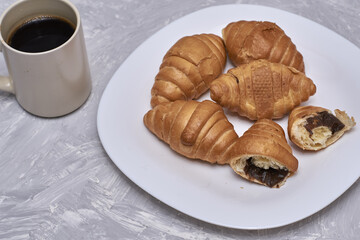 a plate of croissants and a cup of coffee on the table