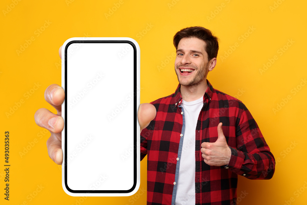Poster cheerful guy showing big white empty smartphone screen and like