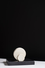 Queso cremoso de cabra sobre piedra negra y fondo negro. Concepto minimalista	